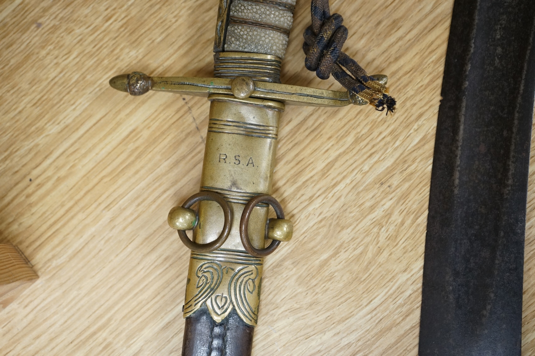 A post 1902 Naval Officer’s Dirk, the regulation blade with crowned fouled anchor, regulation hilt with remains of bullion dress knot in its leather scabbard with brass mounts, locket engraved with owners initials; RSA